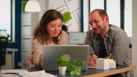 Woman-manager-pointing-on-laptop-showing-new-startup-idea-to-coworkers