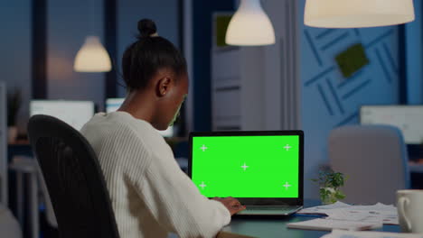 Back-view-of-black-business-woman-looking-at-laptop-with-greenscreen