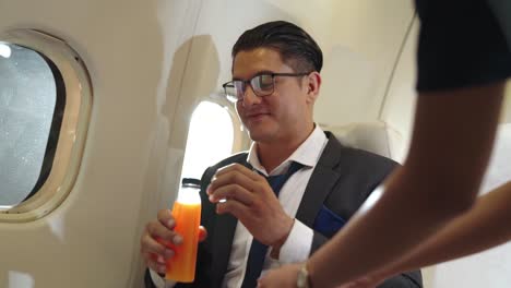 Businessman-have-orange-juice-served-by-an-air-hostess-in-airplane