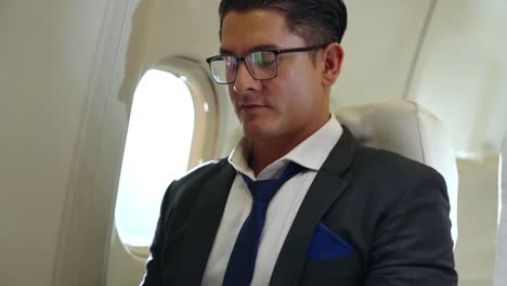 Young-businessman-using-laptop-computer-in-airplane