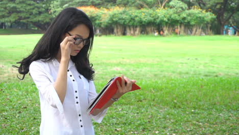 Woman-student-reading-book-in-university-park