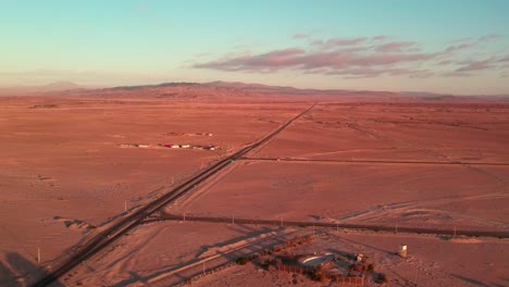 Aerial-view-of-a-unique-street-in-the-northern-desert-of-Chile-with-the-arid-mountains-in-the-background,-sunset,-Coquimbo-Region