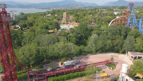 Drone-follows-carriage-of-roller-coaster-quickly-drop-onto-tracks-at-amusement-park-by-Lake-Garda-Italy