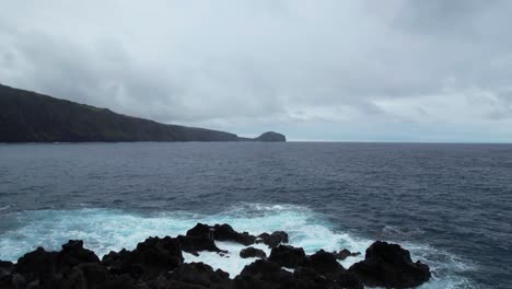 Aerial-parallax-shot-over-volcanic-rocks-in-the-Atlantic-Ocean-with-Morro-de-Castelo-Branco-in-background