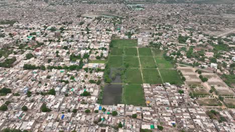 Panning-aerial-shot-of-an-urban-area-with-a-green-field