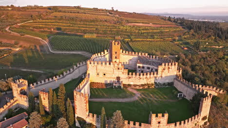 Luftaufnahme-Der-Scaligero-Burg-Von-Soave-Mit-Feldern-Und-Weinbergen-Im-Hintergrund-Bei-Sonnenuntergang-In-Verona,-Italien