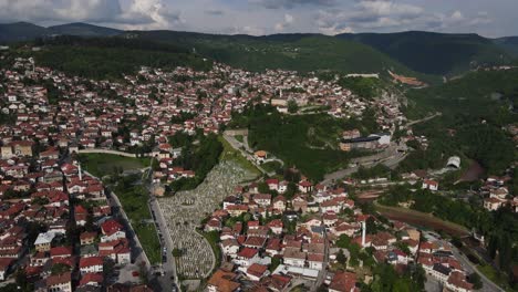 Vista-Aérea-Del-Cementerio-Alija-Izzet-Begovic-En-Bosnia,-Vista-De-La-Ciudad-Construida-En-Las-Laderas-De-Las-Montañas