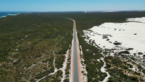 Long-straight-road-through-vast-sandy-terrain-in-Western-Australia