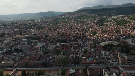 Drone-view-of-the-Bosnian-city-built-at-the-foot-of-the-mountain,-view-of-trees-between-buildings