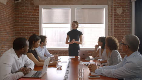 Businesswoman-Standing-To-Address-Boardroom-Meeting