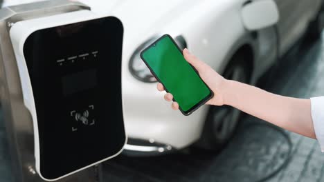 Progressive-concept-of-green-screen-mockup-phone,-EV-car-and-charging-station.