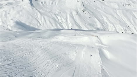 Luftaufnahme-Des-Winterschneesports-Von-Menschen,-Himmel-Und-Snowboard,-Dropdown-Ansicht