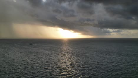 Ferry-boat-sailing-at-sunset-on-calm-sea-with-imminent-Storm-in-Horizon,-Aerial