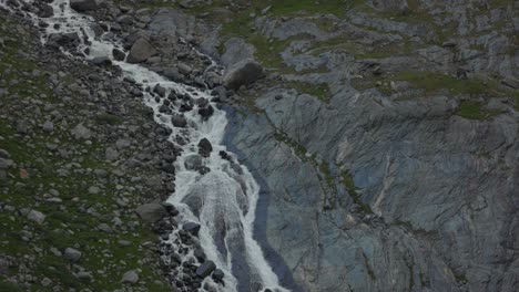 Waterfall-on-mountain-slope-rushing-down-to-valley,-slow-motion-shot,-Fellaria