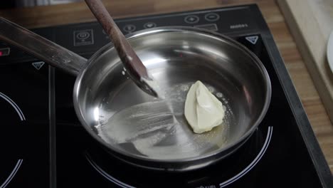 Chef-adds-butter-with-a-spoon-in-hot-pan-to-prepare-cafe-de-paris-butter-sauce,-on-induction-stove
