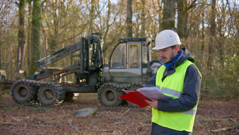 Forest-clearing-heavy-machinery,-employee-reviewing-detailed-report