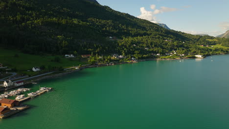 Leuchtendes-Grünblaues-Wasser-Des-Lustra-Fjords,-Während-Das-Sonnenlicht-Den-Bewaldeten-Hügel-Erhellt