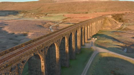 Arched-viaduct-railway-bridge-crossing-barren-Yorkshire-moorland-at-dawn-in-winter