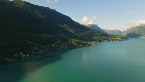 Panoramic-aerial-view-of-Lustra-Fjorden-Norway-as-shadows-from-mountain-cover-hillside-and-water