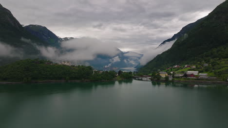 Drone-parallax-around-Sandvatnet-Lake-with-Odda-and-low-clouds-along-alpine-mountain-of-fjord