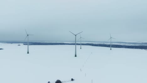 Luftaufnahme-Eines-Windparks-Im-Winter,-Die-Rotorblätter-Drehen-Sich-Und-Erzeugen-Strom-Für-Verbraucher