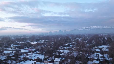 Aerial-trucking-pan-of-suburbs-and-Salt-Lake-City-downtown-skyline-with-inversion-fog-covering-at-morning