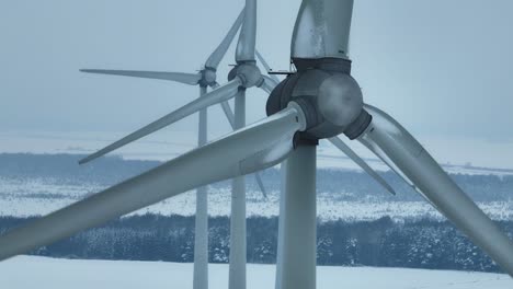 Luftaufnahme-Eines-Windparks-Im-Winter-Aus-Nächster-Nähe,-Die-Rotorblätter-Drehen-Sich-Und-Erzeugen-Strom-Für-Verbraucher