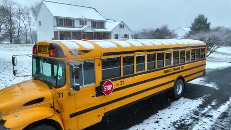 Yellow-school-bus-on-a-snowy-suburban-road-with-houses-in-America