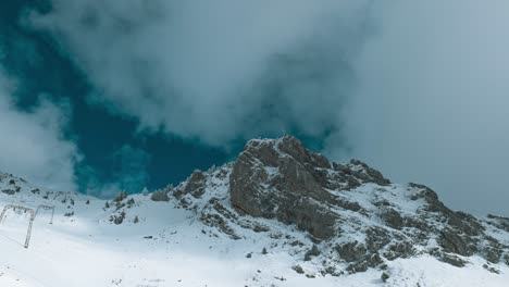 Over-the-peak-of-Engelberg,-partly-covered-in-snow,-cloud-formation-is-shot-in-a-timelapse