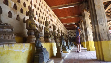 Männlicher-Tourist,-Der-Reihen-Von-Buddha-Statuen-Im-Wat-Si-Saket-In-Vientianne-Betrachtet