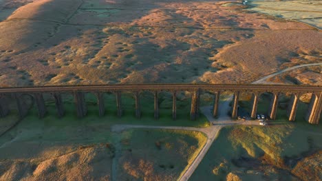 Railway-bridge-with-arches-spanning-barren-English-moorland-at-sunrise-in-winter