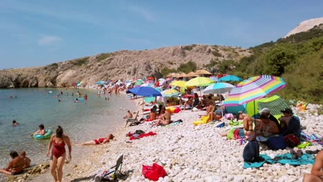 Croacia,-Isla-De-Krk,-Stara-Baška,-Playa-De-Zala,-Video-Colorido-Sobre-La-Hermosa-Bahía-Y-La-Gente-Tomando-El-Sol