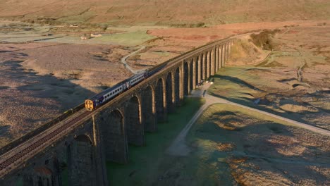 Train-with-two-carriages-crossing-viaduct-bridge-on-cold-winter-morning