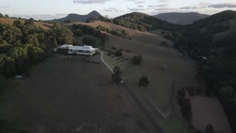 Aerial:-Truck-pulls-up-to-home-atop-rolling-green-country-hills-in-NSW