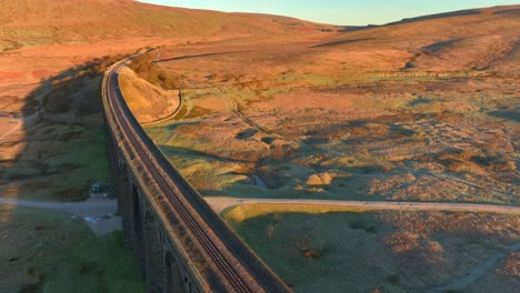 Single-track-railway-bridge-spanning-winter-moorland-landscape-at-sunrise