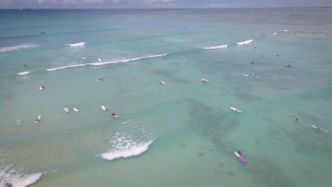 From-above,-a-drone-records-the-perfect-conditions-as-surfers-enjoy-the-waves-in-the-middle-of-the-ocean-in-Hawaii's-paradise