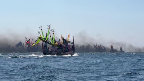 Plano-Medio-De-Barcos-Pesqueros-En-El-Océano-Índico-Durante-El-Festival-Marino-Patik-En-Muncar,-Banyuwangi,-Java,-Indonesia,-Cubierto-De-Humo-De-Escape.