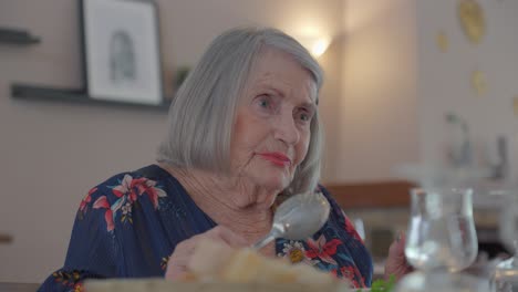 Lovely-older-woman-tastes-her-dinner-from-her-spoon,-slow-motion