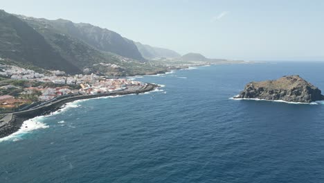 Ocean-waves-roll-and-crash-onto-breakwater-slopes-below-picturesque-town-on-Tenerife-coast