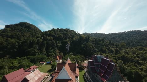 FPV-footage-provides-a-captivating-establishing-shot-of-a-Wat-Thai-temple,-featuring-an-intricate-statue,-highlighting-the-temple's-architectural-beauty-and-cultural-significance
