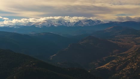 Drone-trucking-pan-tilt-up-to-reveal-snow-capped-mountains-with-wispy-clouds-at-sunset,-Lost-Gulch-Overlook-Boulder-Colorado