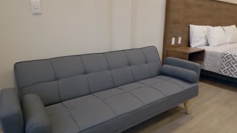 Grey-Couch-Next-To-The-Bed-Inside-The-Hotel