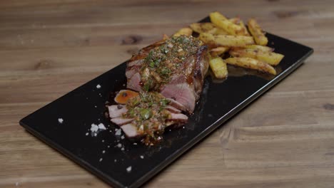 Slices-of-meat-with-chimichurri-and-cafe-en-paris-butter-on-kitchen-board-accompanied-with-french-fries,-argentinian-food