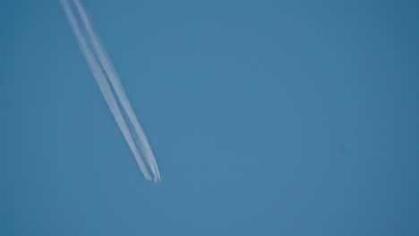 Tilt-up-shot-of-a-plane-cruising-the-sky-leaving-a-vapor-trail-behind