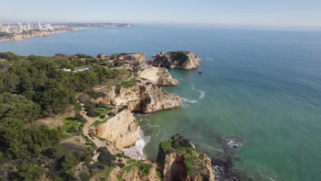 Cinematic-rocky-coast-in-Portimao,-Portugal,-aerial-orbit-on-a-summer-day