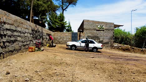 Junge-Leute-Waschen-Auto-In-Kenia-–-Ländliche-Dorfstadt-Kenias-Mit-Dem-Kilimandscharo-Im-Hintergrund