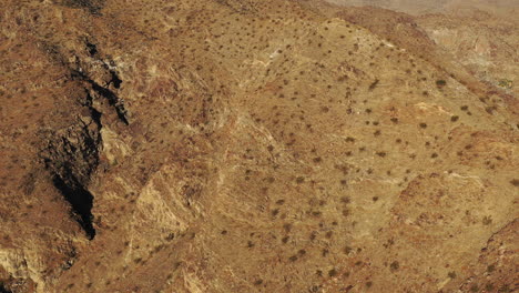 Drone-shot-rising-slowly-over-barren-desert-mountain-peaks