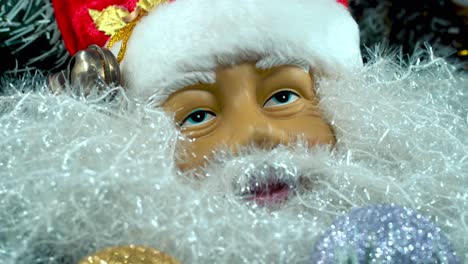 Weihnachtsmann-Spielzeug-Mit-Rotem-Hut-Und-Glöckchen,-Großer-Weißer-Bart,-Weihnachtsdekoration,-Traditionelle-Feiertagsgeschenke,-Neujahrsdekoration,-Glänzendes,-Farbenfrohes-Setup,-Kreative-Nahaufnahme-Mit-Sanfter-Neigung-Nach-Unten,-Grüner-Baum