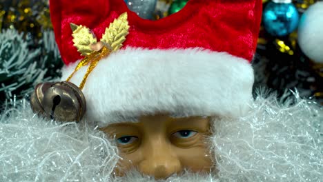 Santa-Claus-toy-in-a-red-hat-with-bells,-Christmas-decoration,-traditional-holiday-presents,-new-year-decor,-shiny-colorful-gifts,-Detailed-close-up-smooth-tilt-up-shot,-4K-video