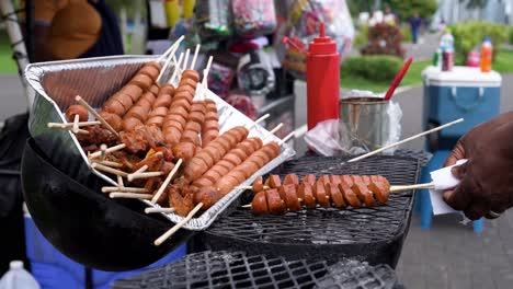Selling-street-food-in-Panama:-picking-skewered-food-being-grilled-,-with-bottles-of-barbecue-sauce